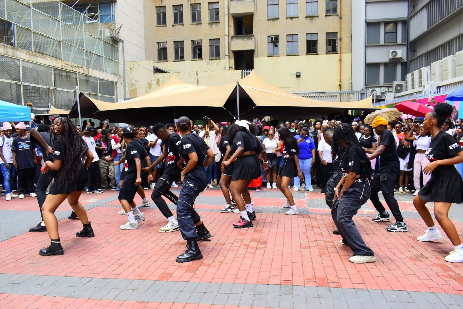 Dancers performing in front of a large crowd at a campus event.