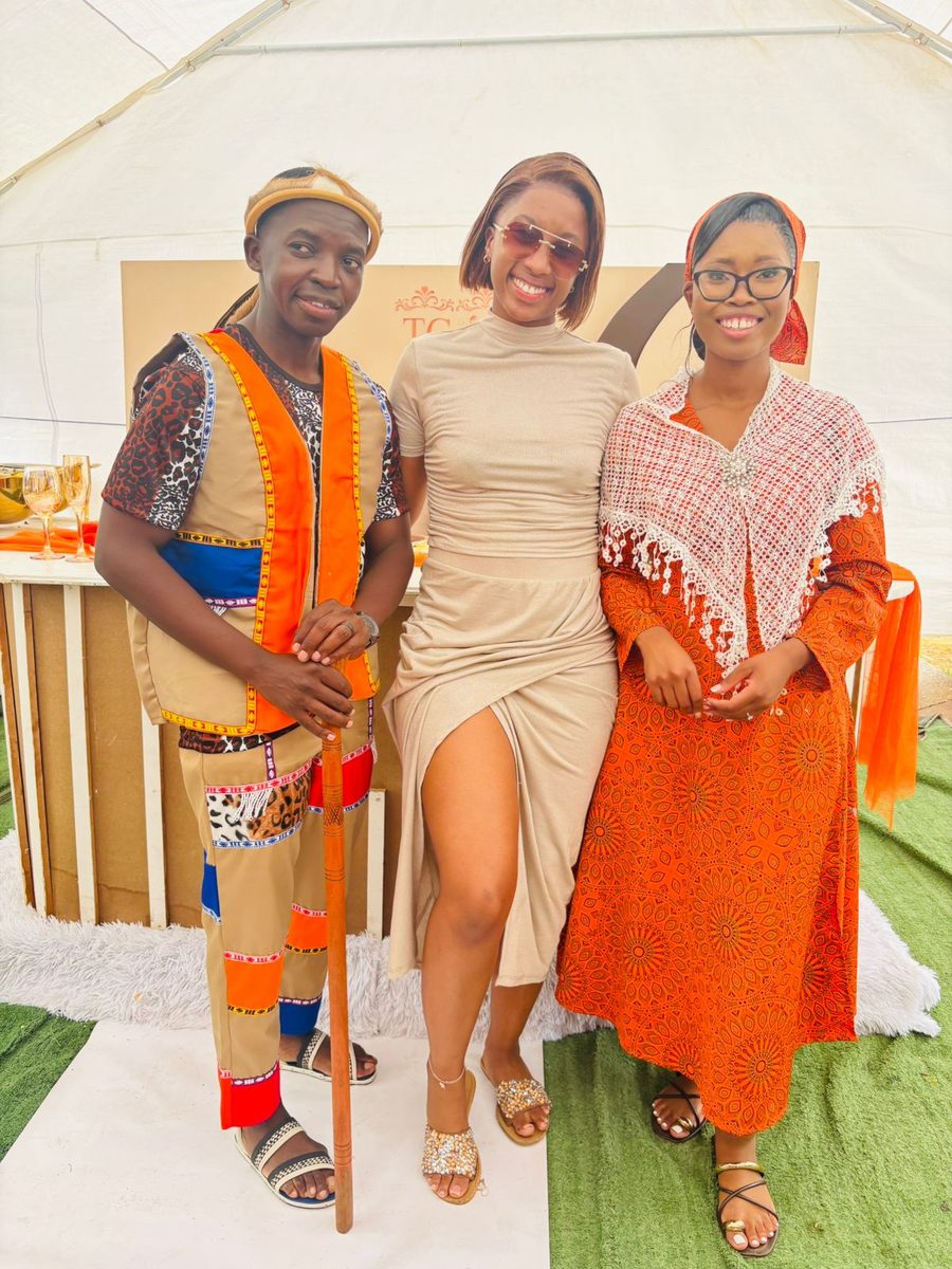Three people in colourful traditional attire posing together at a celebration.